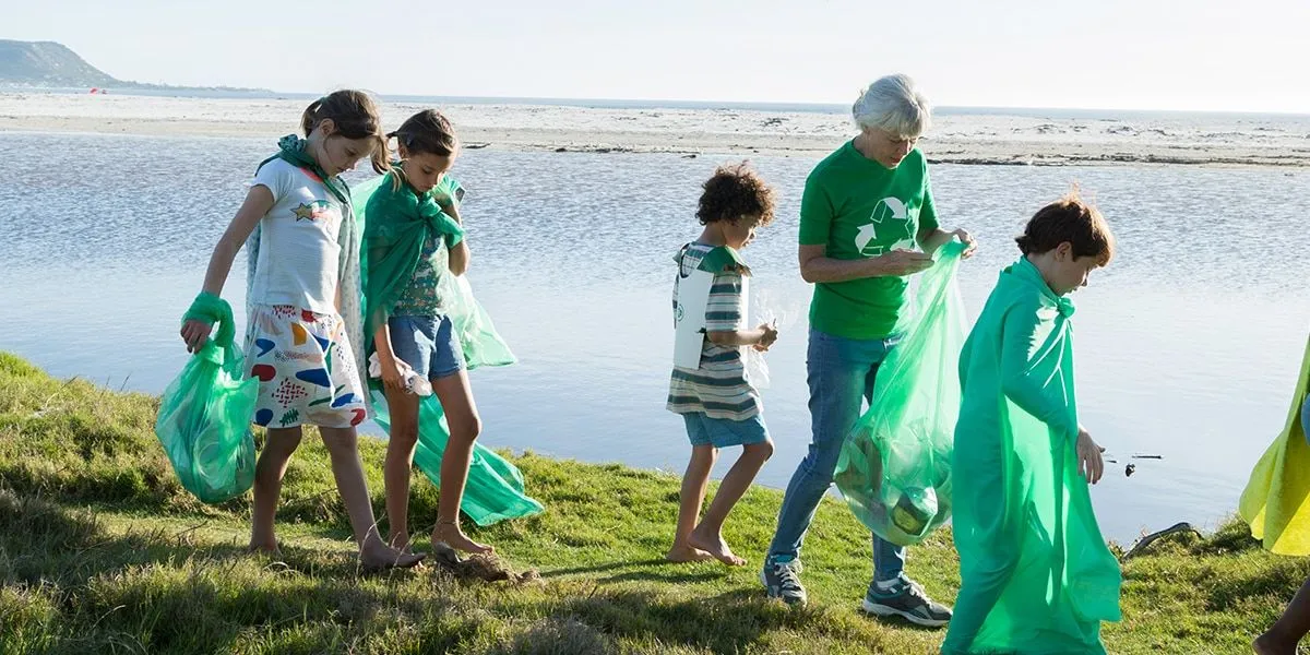Bambini con la nonna che raccolgono i rifiuti da una spiaggia