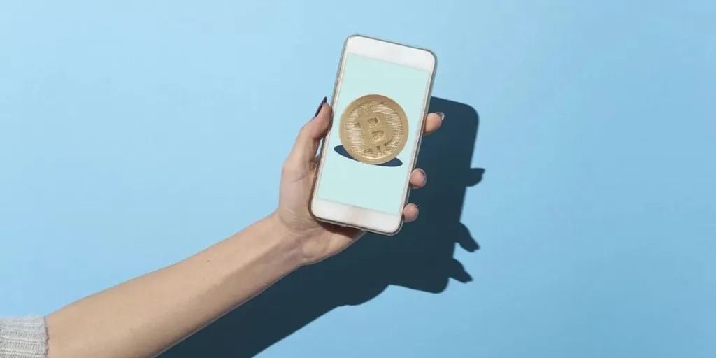 smartphone tenuto in mano con simbolo del Bitcoin