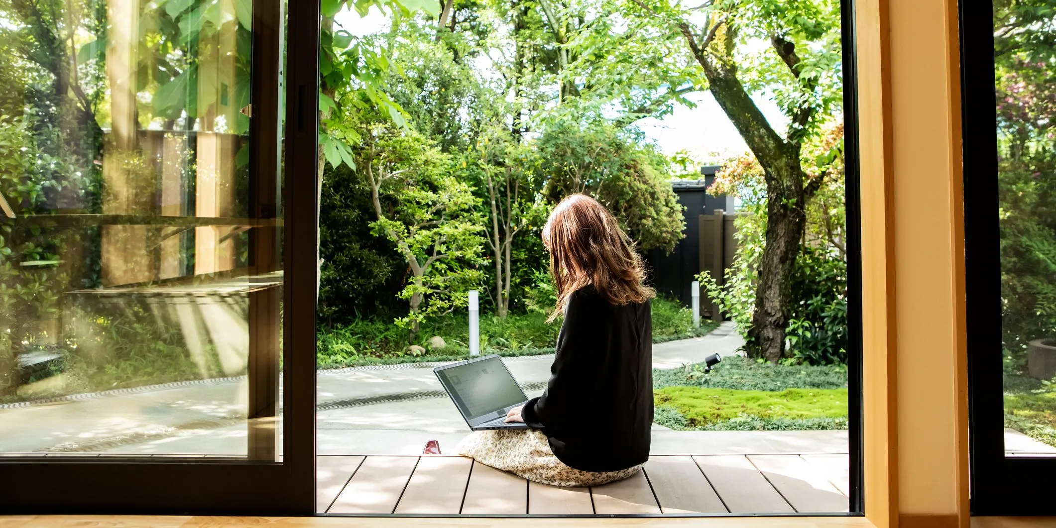 Donna al PC in veranda con giardino rigoglioso